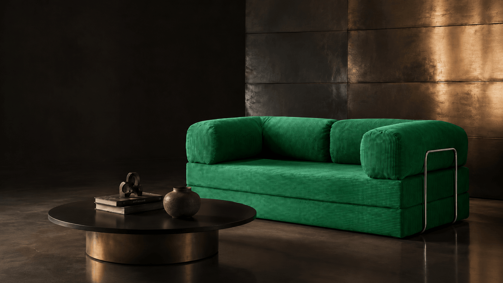 A modern green upholstered sofa with thick armrests and a slim metal side rail, shown in a dark interior setting next to a round black coffee table.